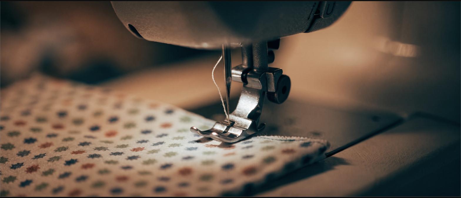 A sewing machine stitching a hem along patterned cotton fabric